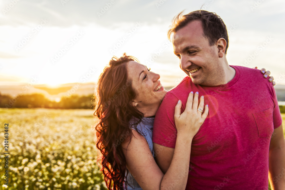 Man and woman on the daisy field at sunset