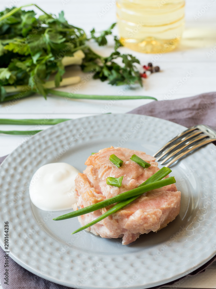 Canned tuna in its own juice with green onions on a plate. selective focus