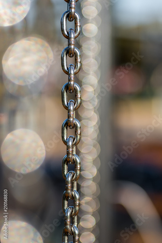 Many vertical hanging stainless steel chains in varying depth of field and focus