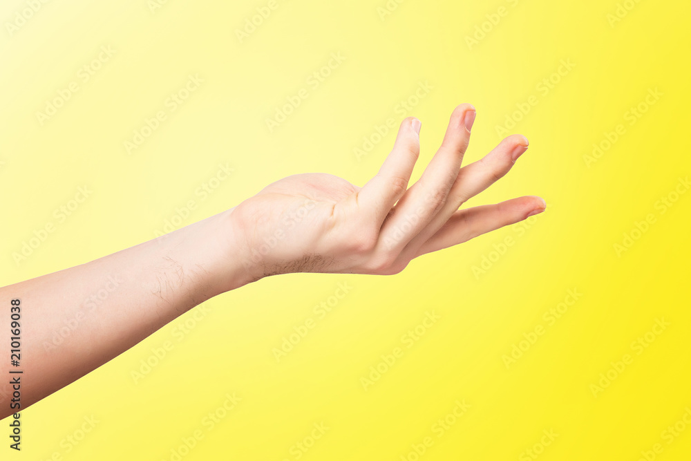 CLoseup mockup of male caucasian hand making holding gesture with opened palm isolated at yellow background.