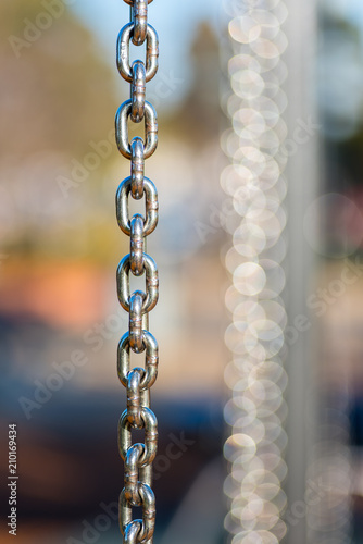 Many vertical hanging stainless steel chains in varying depth of field and focus