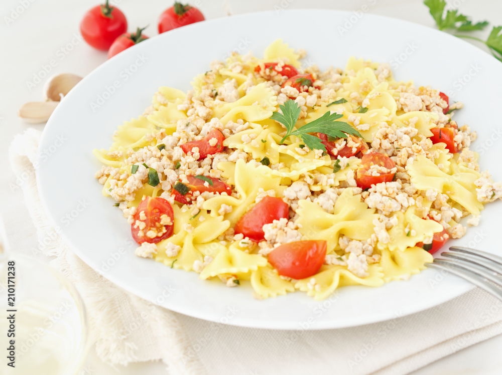 farfalle pasta with tomatoes, chiken meat, parsley on white stone background, low-calorie diet, side view farfalle pasta with tomatoes, chiken meat, parsley on white stone background, low-calorie diet, side view