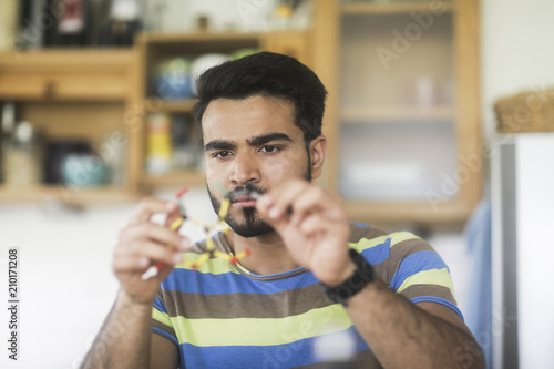 Man sitting at table making a frame structure