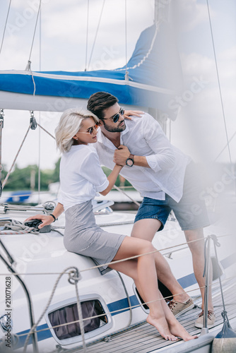 selective focus of young couple in love hugging and looking away on yacht