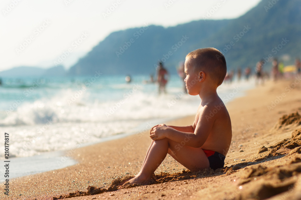 Little boy sitting on beach.