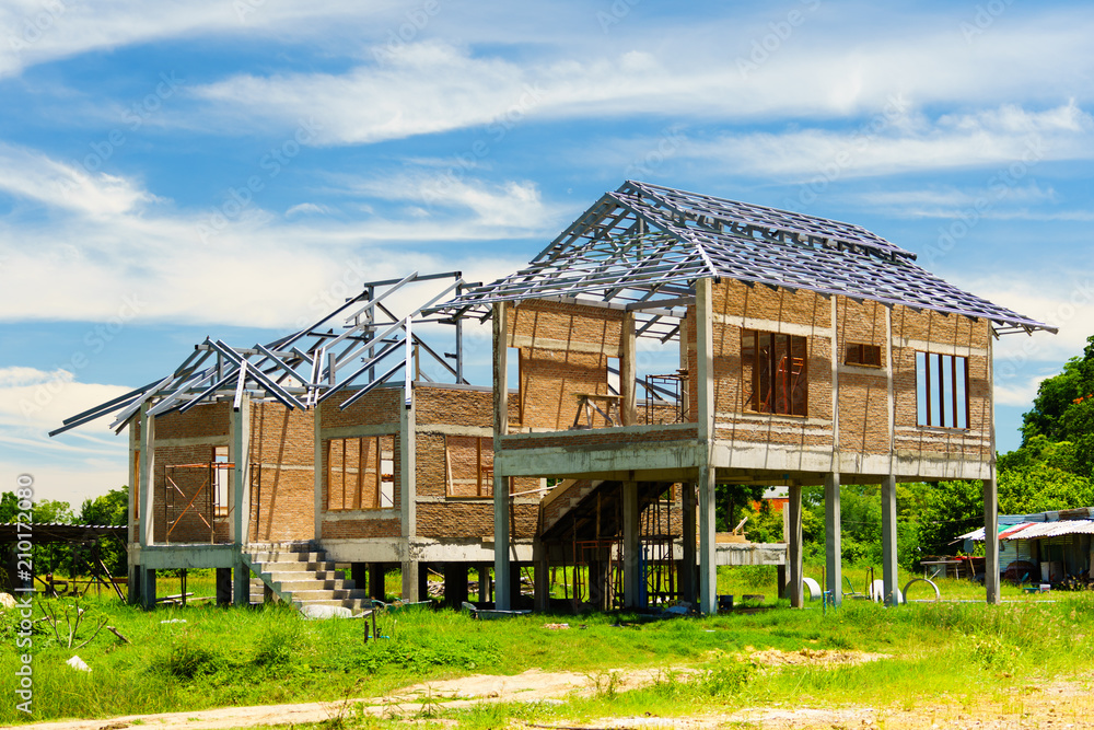 New residential construction house framing against a blue sky ans green forest New residential construction house framing against a blue sky ans green forest