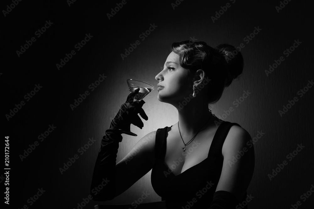 Obraz premium Dramatic portrait of a beautiful woman with glass of martini .