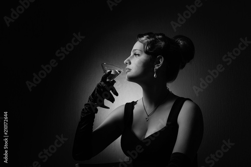 Dramatic portrait of a beautiful woman with glass of martini .