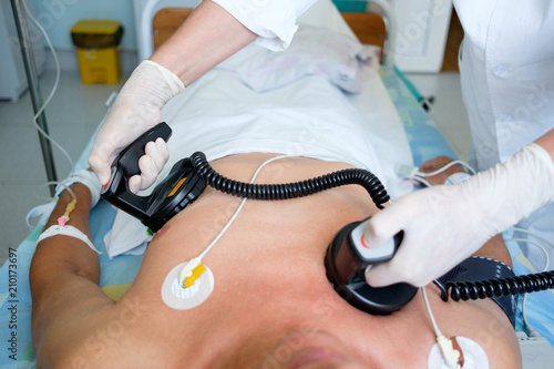 hands of doctor holding defibrillator electrods, performing defibrillation or electropulse therapy photo