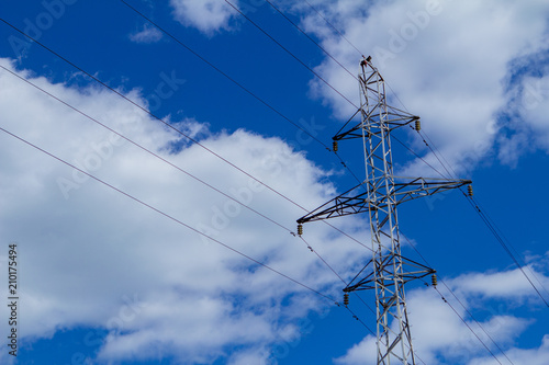 Electric high voltage tower with electric line against clouds blue sky