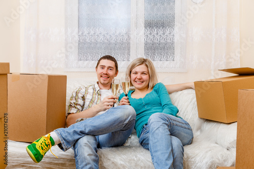 Photo of man and woman with wine glasses with wine sitting on sofa among cardboard boxes © nuclear_lily