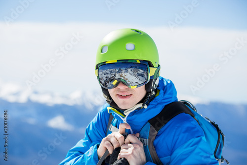 Photo of man in helmet and glasses with reflection of mountains on winter day