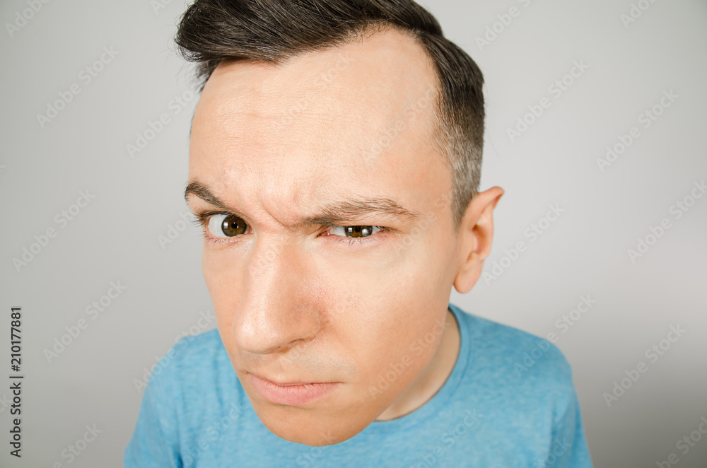 Young guy gloomy look forward, dressed in a blue t-shirt on a light background. Young guy gloomy look forward, dressed in a blue t-shirt on a light background.
