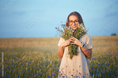 girl with a bouquet of daisies and cornflowers in the field.