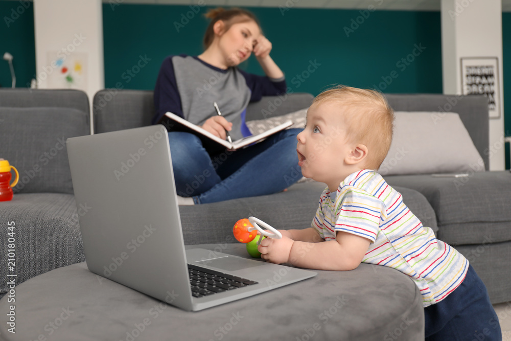 Cute little baby with laptop with tired mother at home Cute little baby with laptop with tired mother at home