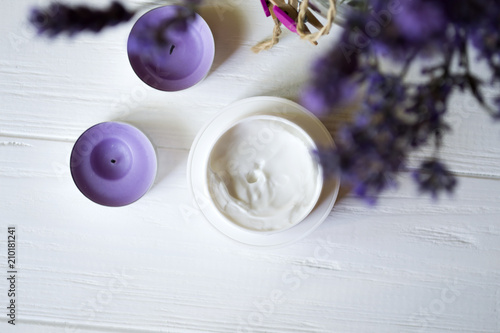 Lavender flowers  candles and cream on a white wooden background. Beauty care.