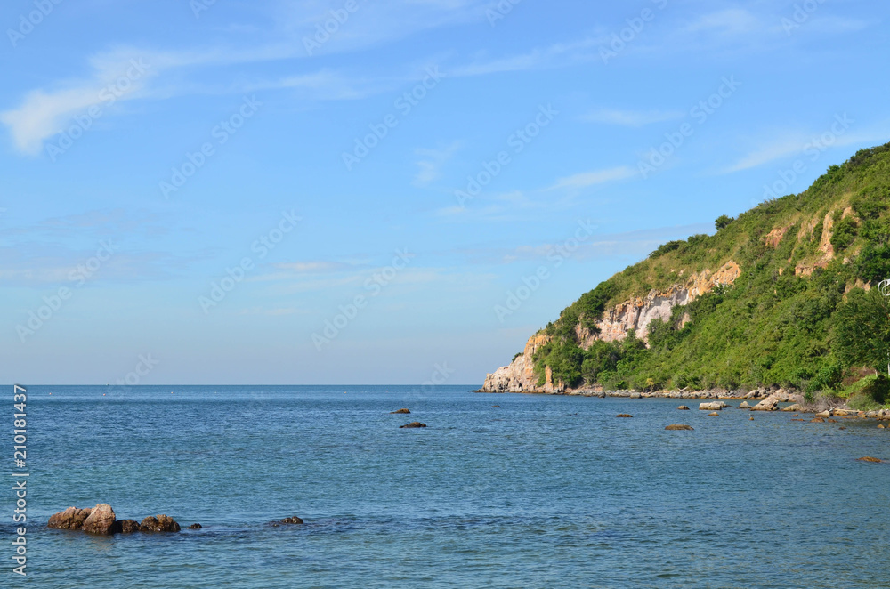 Beautiful calm sea with rock and mountain on blue sky day