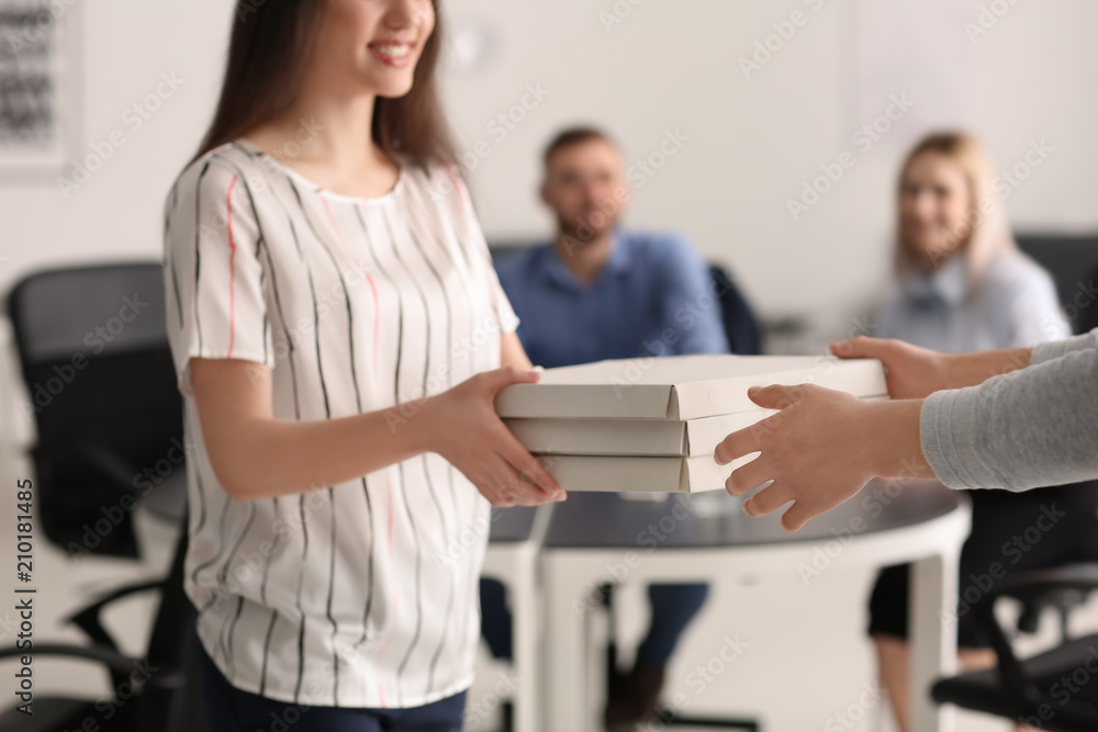 Young man delivering cardboard pizza boxes to client in office Young man delivering cardboard pizza boxes to client in office
