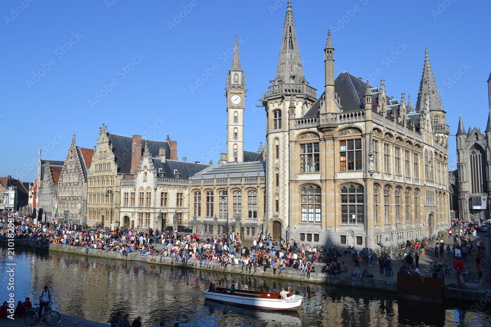 Young people, mainly students, relax by the edge of a canal in Ghent, Belgium