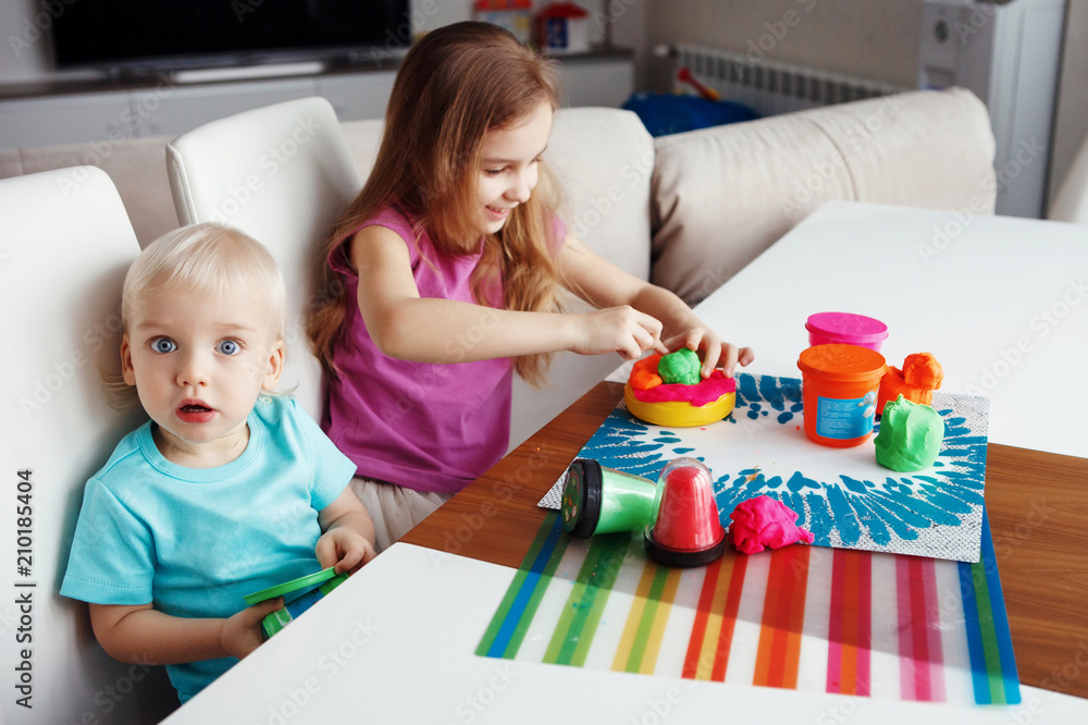 Fototapeta premium Two happy children Blond boy and girl playing sitting at table at home