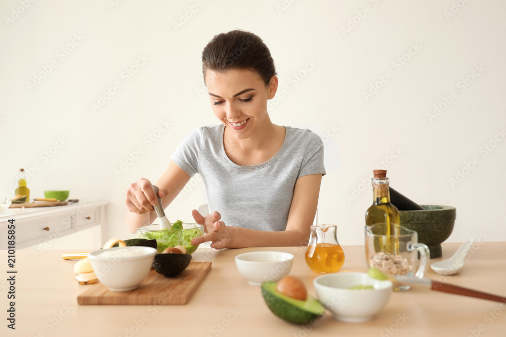 Young woman making nourishing mask with avocado in kitchen Young woman making nourishing mask with avocado in kitchen