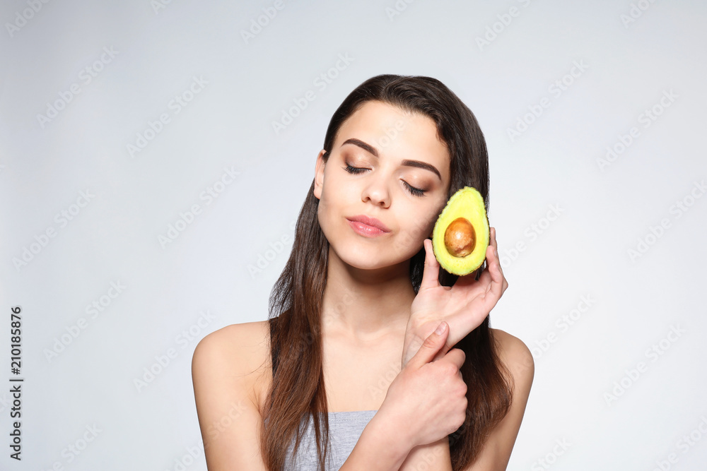 Beautiful young woman with avocado on light background Beautiful young woman with avocado on light background