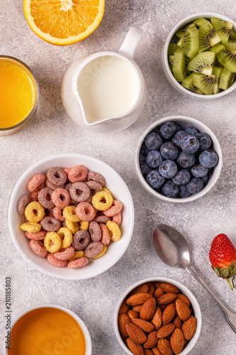 Breakfast with colorful cereal rings, fruit, milk, juice.