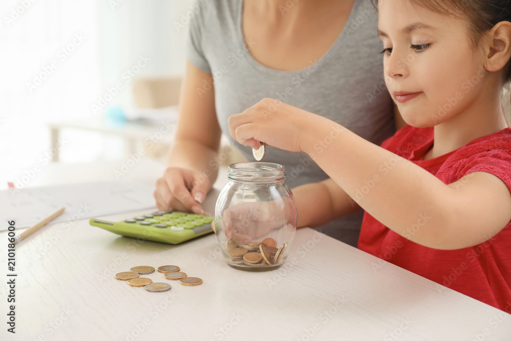 Little girl with her mother sitting at table and counting money indoors. Money savings concept Little girl with her mother sitting at table and counting money indoors. Money savings concept