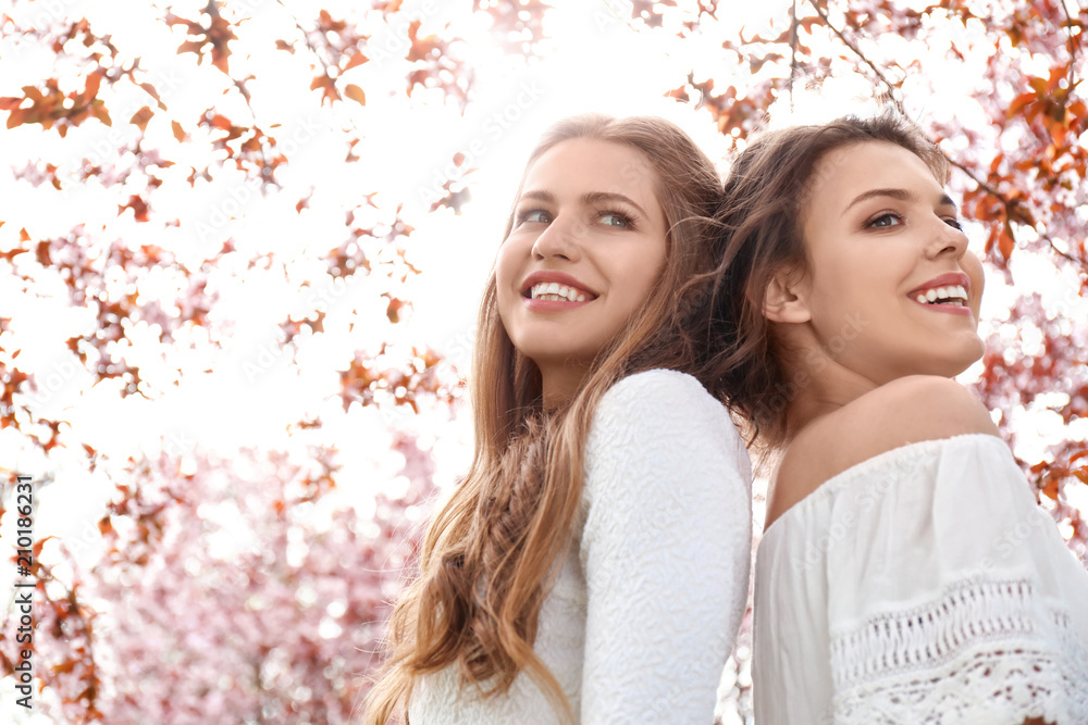 Beautiful young women in park with blooming trees on spring day Beautiful young women in park with blooming trees on spring day