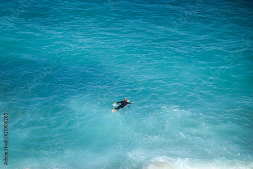 An aerial view of surfer waiting for a wave in the ocean on a clear day