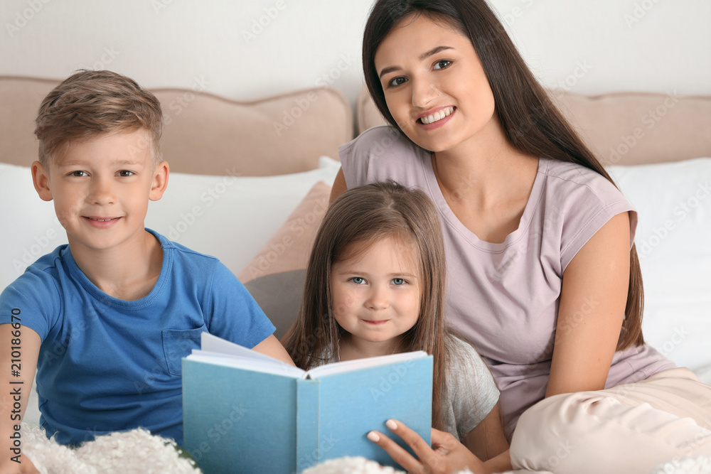 Mother and her children reading book together at home Mother and her children reading book together at home