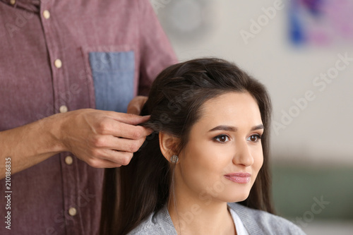 Professional hairdresser working with client in beauty salon