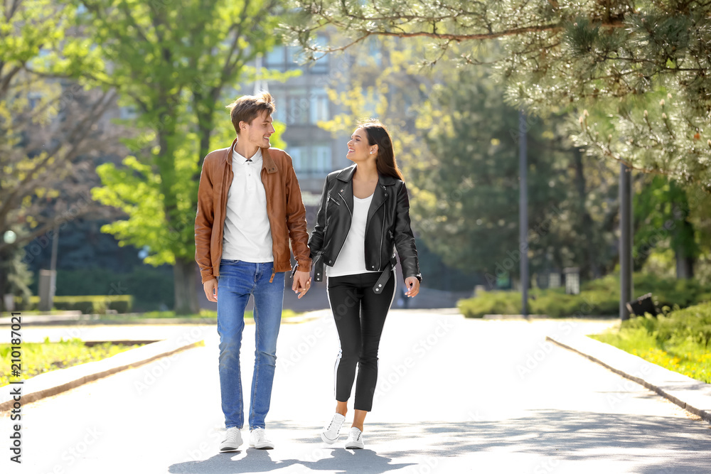 Happy young couple walking together in city park