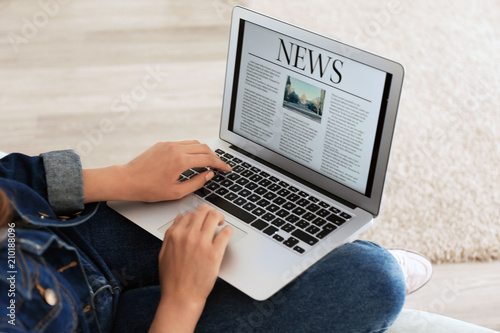 Woman reading news on laptop screen at home