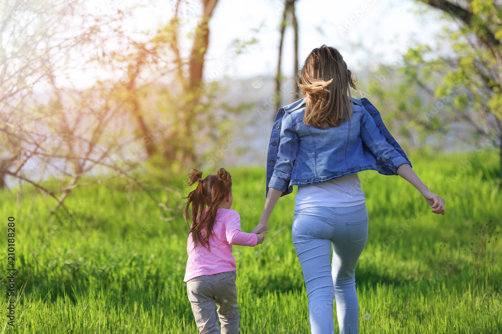 Fototapeta premium Little girl with mother walking in park