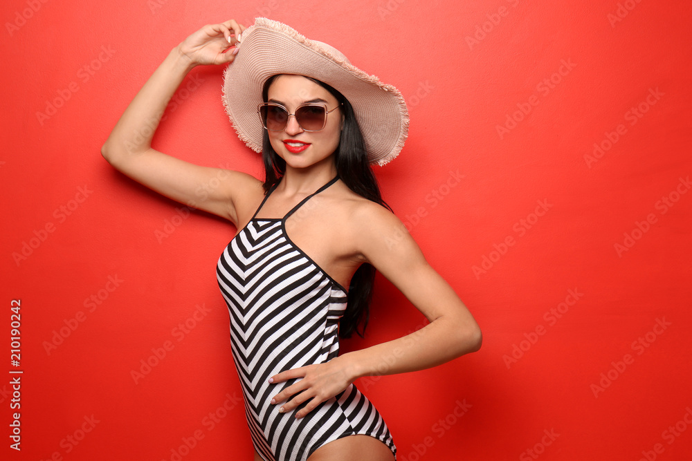 Beautiful young woman in swimming suit with sunglasses and hat on color background Beautiful young woman in swimming suit with sunglasses and hat on color background