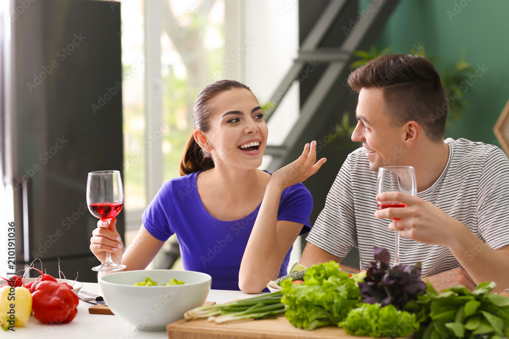 Young couple drinking wine while cooking together in kitchen Young couple drinking wine while cooking together in kitchen