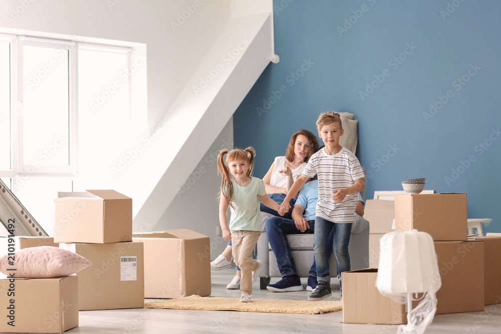 Happy family with cardboard boxes and belongings indoors. Moving into new house Happy family with cardboard boxes and belongings indoors. Moving into new house