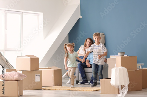 Happy family with cardboard boxes and belongings indoors. Moving into new house