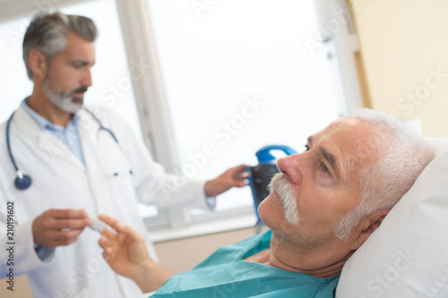 doctor with sick old man lying in hospital bed