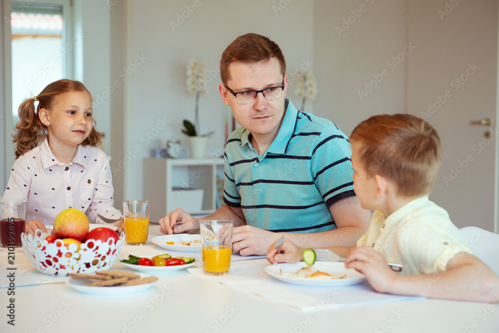 Happy father with his children talking at the breakfast at home Happy father with his children talking at the breakfast at home