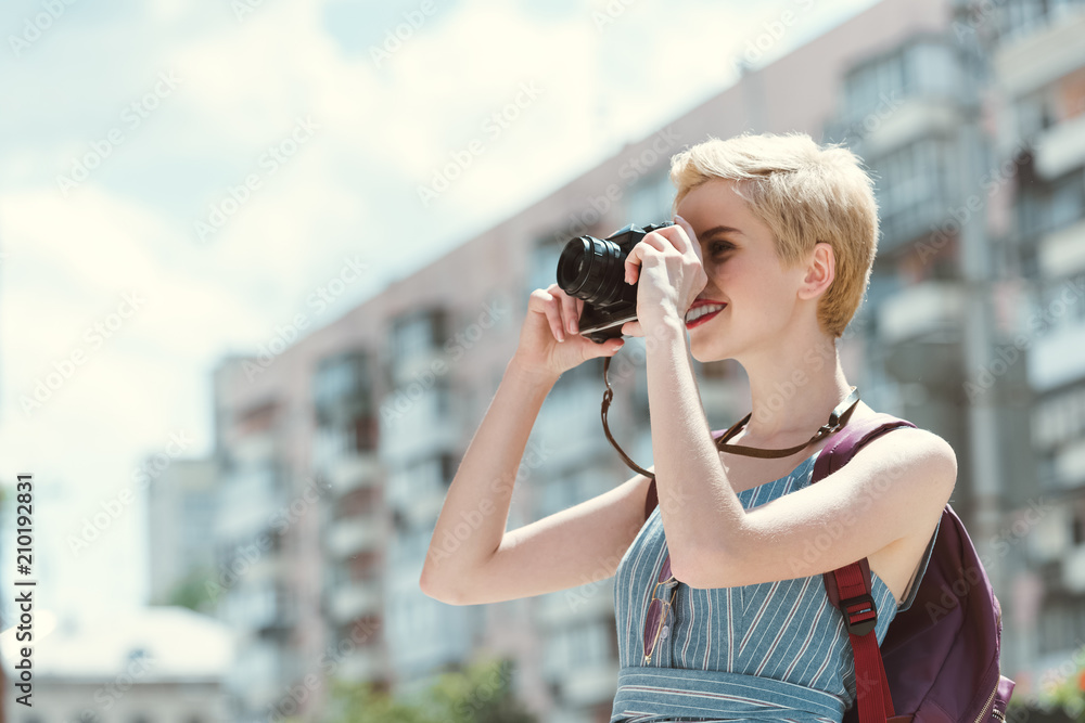 young woman taking photo on camera in city