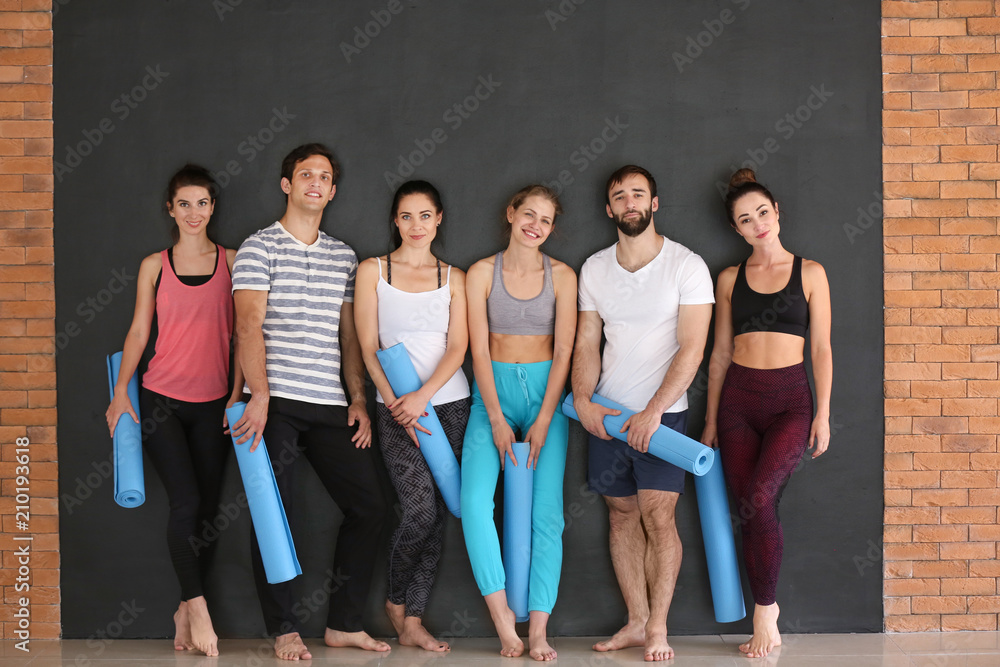 Group of people with yoga mats on dark background