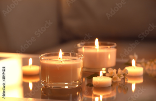 Burning candles on glass table indoors