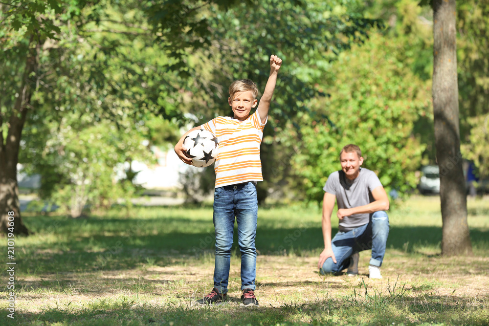 Fototapeta premium Happy father and son playing football in park