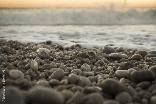 Pebbles on a beach at sunset with gentle surf in the background, Oludeniz, Turkey