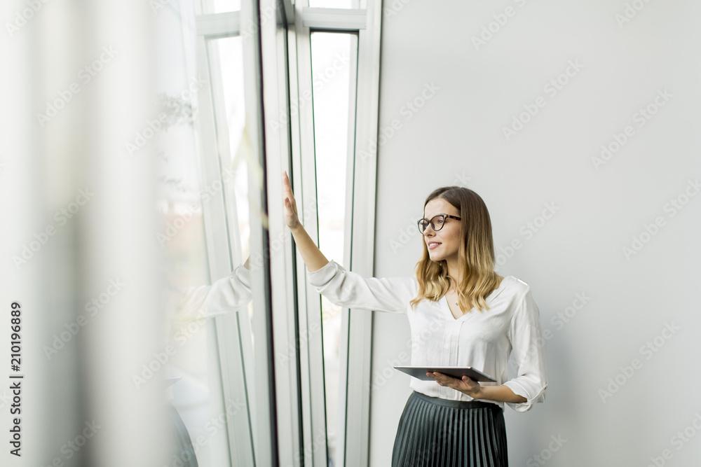 Elegant businesswoman standing in office with digital tablet Elegant businesswoman standing in office with digital tablet