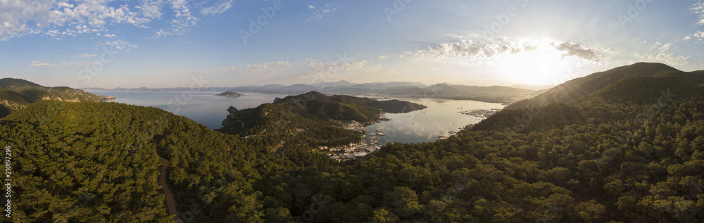 Aerial over a small harbour town surrounded by mountains and forest at sunrise, Fethiye, Turkey