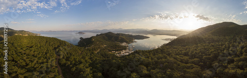 Aerial over a small harbour town surrounded by mountains and forest at sunrise, Fethiye, Turkey