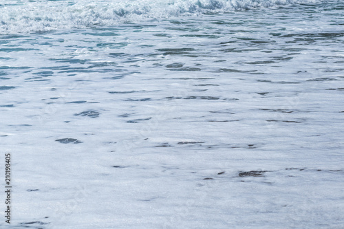 Texture of foamy wave on the beach, background